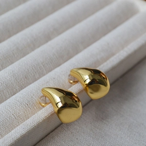Macro shot of polished gold water drop earrings on a premium linen display tray