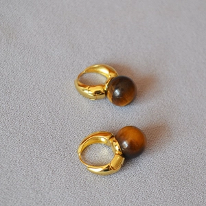 Détail de boucles d'oreilles vintage en laiton avec pierre œil de tigre et fini doré