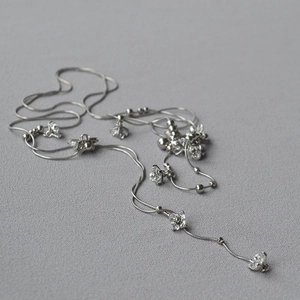 Dettaglio macro della collana a catena a serpente argento con ciondoli a fiori