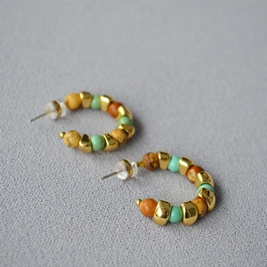 Detail of C-shaped hoop earrings featuring bohemian natural stone beads and gold spacers