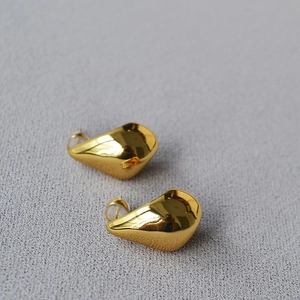 Detailed close-up of irregular gold water drop earrings with smooth mirror finish