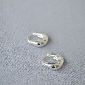 Detailed close-up of chunky silver teardrop earrings with a polished mirror finish