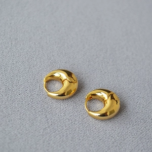 Close-up of minimalist gold plated thick hoop earrings with a high-polished mirror finish
