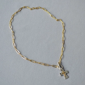 Détail du collier à maillons trombone avec pendentif croix bicolore et fermoir à bascule