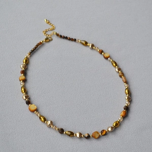 Detailed view of beaded necklace with tiger eye stones, pearls and golden lobster clasp