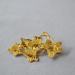 Macro detail of golden leaf brooch showing textured layers and polished metallic finish