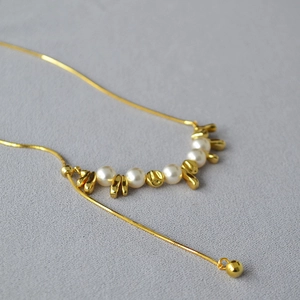 Vista macro della collana a catena serpente dorata con perle e design a Y regolabile chic