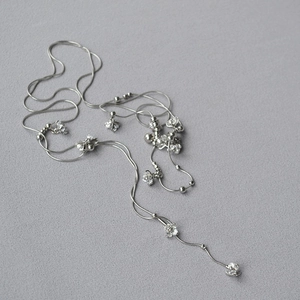 Dettaglio di una collana lunga in argento con fiori di cristallo e perline metalliche