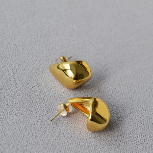 Macro shot of minimalist gold drop earrings with polished finish and secure backings