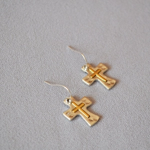 Detail of two-tone cross earrings with hammered silver texture and gold plating
