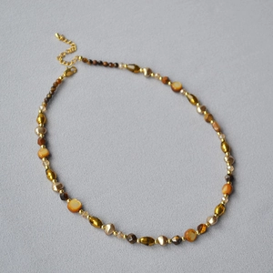 Detail of tiger eye beads and irregular pearls on necklace with gold lobster clasp