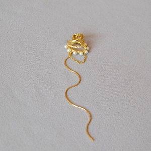 Close-up of golden layered ear cuff with pearls, rhinestones and elegant long chain tassel