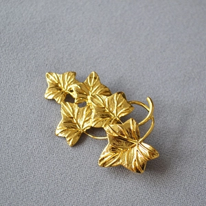 Macro detail of the polished golden vine leaf brooch with realistic vein textures