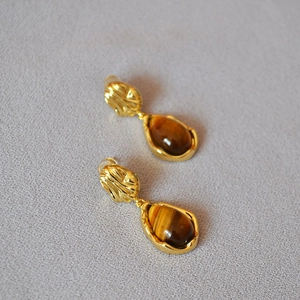 Détail de boucles d'oreilles en œil de tigre en forme de goutte et finition dorée