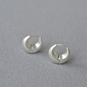 Macro view of matte silver chunky hoop earrings with a brushed metallic texture