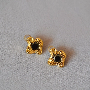 Macro view of gold-plated flower stud earring with pleated texture and black zircon