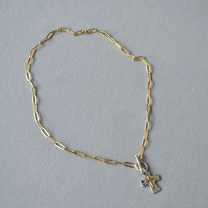 Détail du collier à maillons trombone avec pendentif croix bicolore et fermoir à bascule