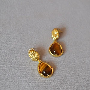 Détail de boucles d'oreilles en œil de tigre en forme de goutte et laiton doré
