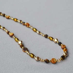 Macro detail of retro tiger eye stone beads with polished amber and gold metallic accents