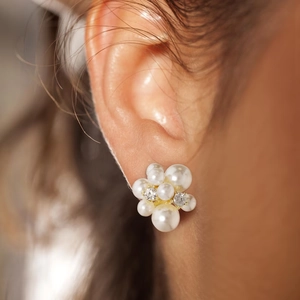 Gros plan de boucles d'oreilles orchidée en perles blanches et cristaux sur métal doré