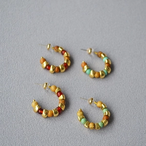 Detail of vintage beaded C-shaped hoop earrings with natural stones and gold spacers
