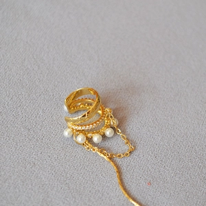 Macro detail of 3-layer gold ear cuff with pearls, zircon, and long tassel chain