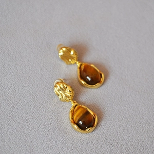 Détail de boucles d'oreilles vintage en laiton avec œil de tigre et texture martelée