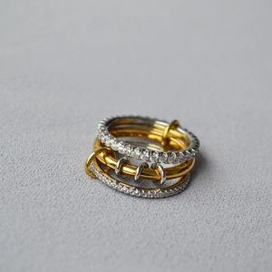 Close-up of stacked multi-link rings with silver diamond band and gold circles