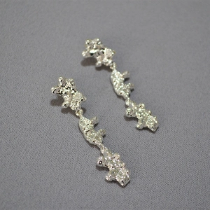 Macro detail of silver tone lava texture earrings with irregular artistic flowing lines