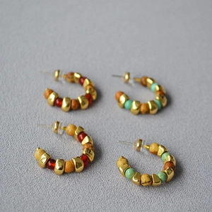 Detail of C-shaped hoop earrings with polished gold beads and natural stone beads