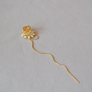 Close-up of golden multi-layer ear cuff with delicate pearls and dangling fringe chain