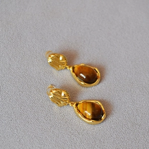 Détail de boucles d'oreilles vintage en œil de tigre et laiton doré à texture ondulée