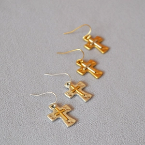 Detailed view of vintage hammered texture cross earrings in gold and silver mixed tones