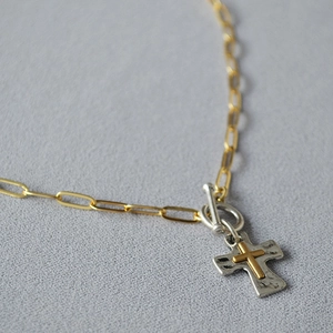 Vue détaillée du pendentif croix bicolore vintage et de la chaîne à trombones dorée