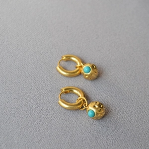 Vintage gold textured ball earrings with turquoise inlay on grey fabric background