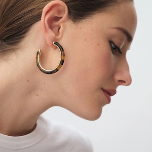Detail of tortoise shell C-shape hoop earrings with gold inner lining on model