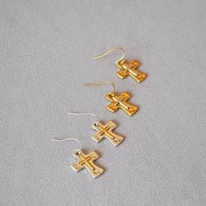 Detail view of retro brass cross earrings with hammered texture and mixed metal finishes