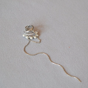 Detail of silver pearl ear cuff with long tassel chain and micro-set zircon accents