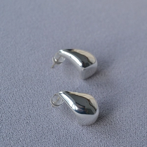 Macro shot of polished silver teardrop earrings with smooth metallic mirror finish