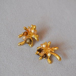 Detail of tiger eye bead and crystal cluster studs in retro gold-plated floral design