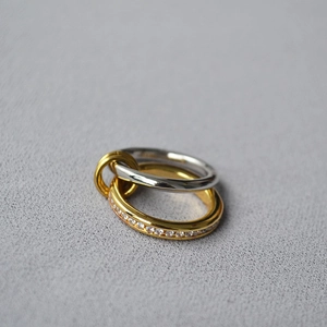 Detail of three-intertwined rings featuring a gold crystal-encrusted band and silver band