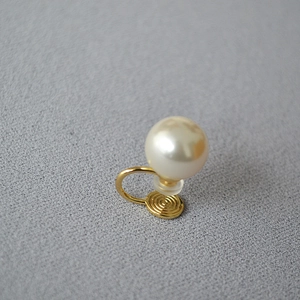 Gros plan sur un élégant clip d'oreille en perle avec métal doré et design en spirale