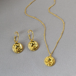 Détail d'un ensemble de bijoux licorne en laiton doré avec collier et boucles d'oreilles