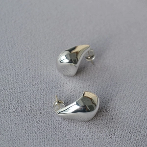 Macro shot of silver liquid teardrop earrings with mirror polished finish and silicone backs