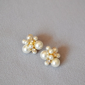 Détail de boucles d'oreilles fleur avec perles blanches et cristaux sur métal doré