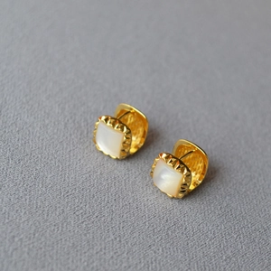 Macro shot of geometric brass gold earrings with square white mother of pearl inlay