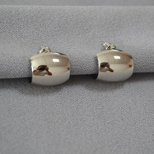 Detailed close-up of chunky silver C-shape stud earrings with polished mirror finish