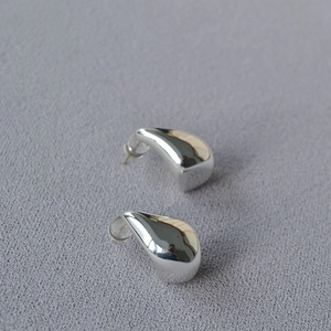 Macro shot of silver teardrop earrings with high-polish finish and soft silicone backings