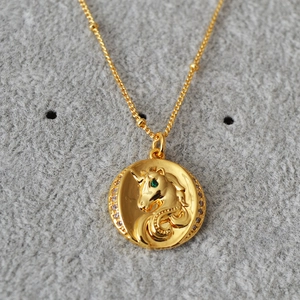 Collier en laiton doré avec pendentif licorne rond orné d'une gemme verte