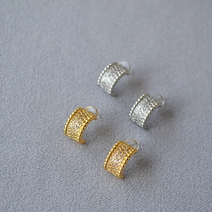 Detailed view of C-shaped gold and silver earrings with micro-set zircon and beaded edges